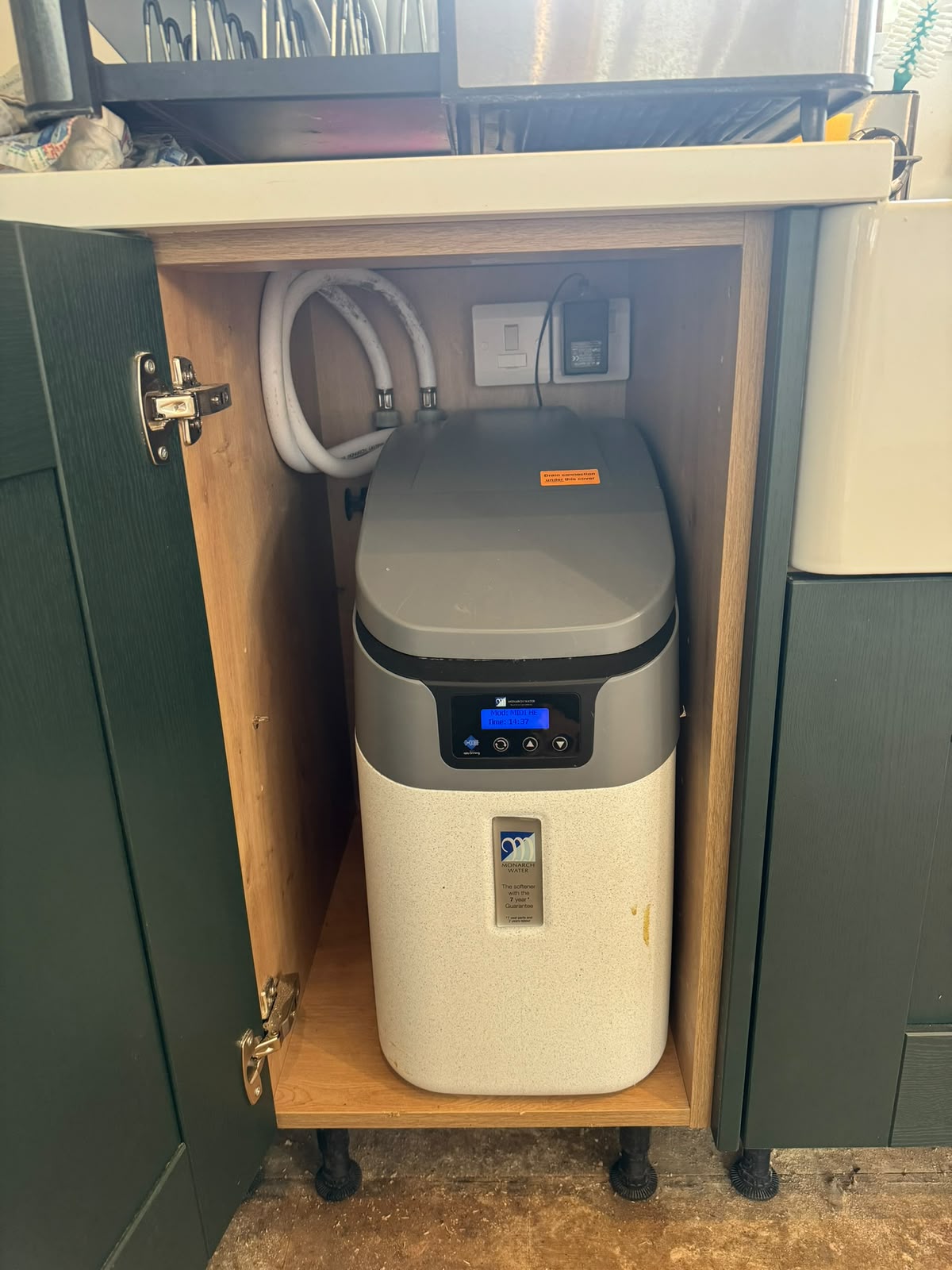 Compact water softener installed inside a kitchen cabinet